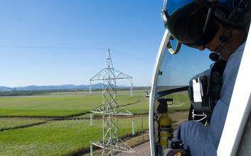 Helicopter inspecting a transmission line and tower