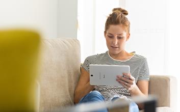 Woman on a tablet device sitting on the couch