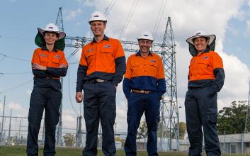 Four staff in PPE standing in front of transmission towers