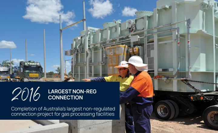 Two Powerlink workers stand in front of machinery on the back of trucks
