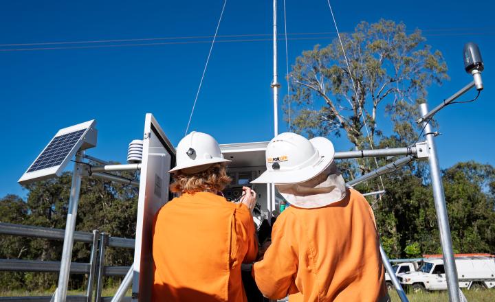 two men in PPE installing weather station