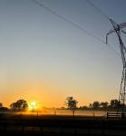 Trees, fence and transmission tower at sunrise